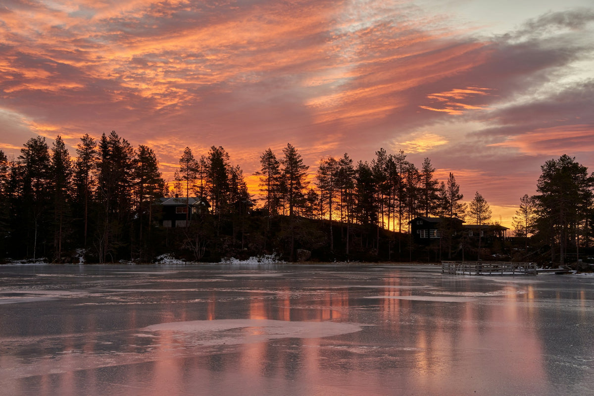 Sunrise over a frozen lake with cabins